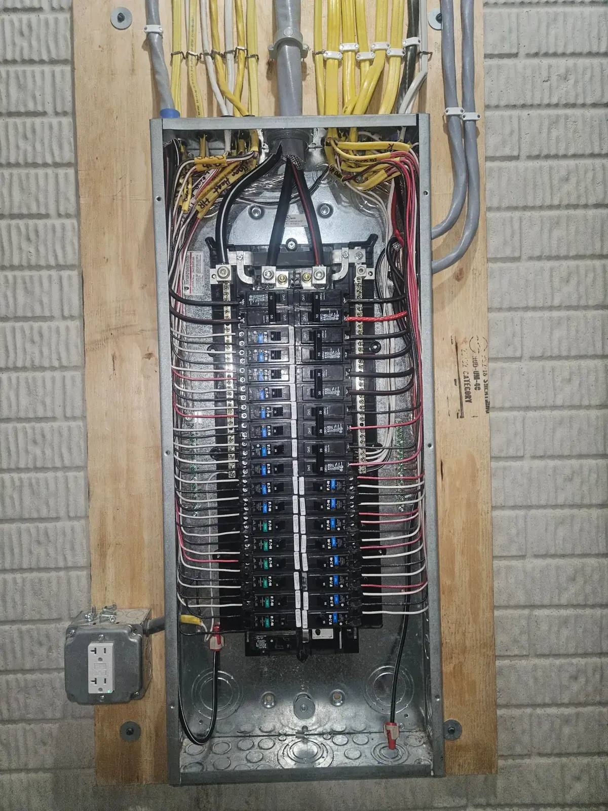 Residential breaker panel with the cover removed, showing two columns of breakers and yellow branch-circuit cables entering from the top